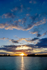 Sunset over the lake on a background of blue sky