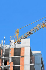 Crane and building construction site against blue sky