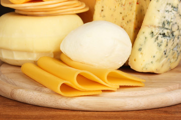 Various types of cheese on wooden board close up