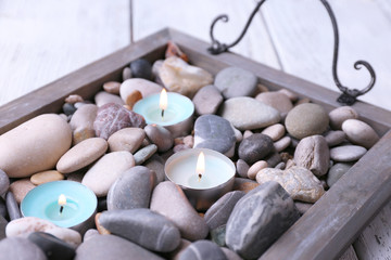 Fototapeta na wymiar Candles on vintage tray with sea pebbles, on wooden background