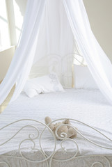 white bed with a baldachin by krausens and soft toy