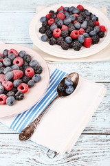 Iced berries on plate, on color wooden background