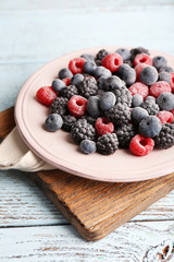 Iced berries on plate, on color wooden background
