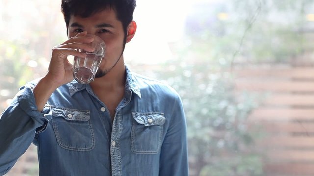 窓際で水を飲む男性1