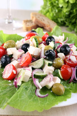 Greek salad in plate served on napkin on wooden background