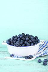 Tasty ripe blueberries in bowl, on wooden table