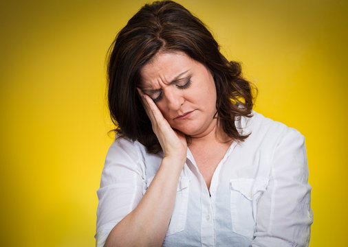 Headshot Depressed, gloomy woman on yellow background 