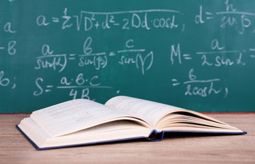 Book on wooden table on blackboard background