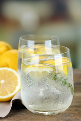 Tasty cool beverage with lemon and thyme, on light background