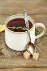 Cup of tasty herbal tea with thyme and lemon on wooden table
