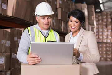 Warehouse worker and manager looking at laptop