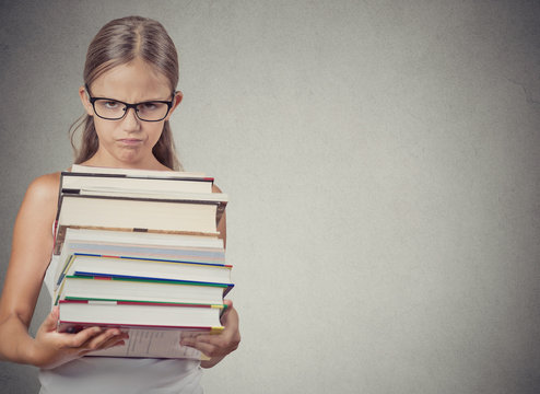 Too much to learn! Unhappy student holding huge stack of books