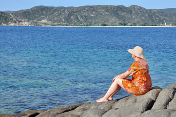 Woman sitting on the rock near the sea meditating