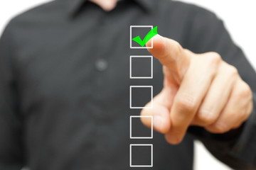 Young businessman checking mark on checklist with marker.