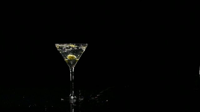 Two olives falling into a glass of martini. Slow motion