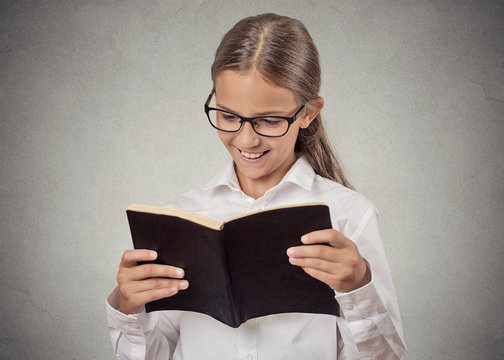 Teenage girl reading a book smiling isolated grey background 