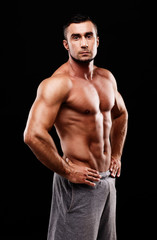 Fototapeta na wymiar Serious muscular sportsman over black background