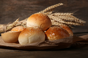Tasty buns with sesame on wooden background