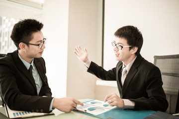 Two Businessmen Having Informal Meeting In Modern Office