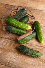 Cucumbers in wicker basket on wooden background