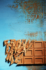 Milk chocolate bar on color wooden background