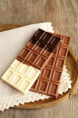 Chocolate bars on napkin, on tray, on wooden background