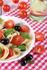 Spaghetti with tomatoes, olives and basil leaves