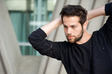 Handsome male fashion model posing with hands behind head