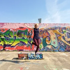 Zelfklevend Fotobehang Mädchen springt vor Graffiti © Robert Kneschke
