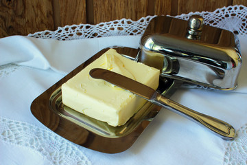 Butter in the butter-dishand and knife on a white tablecloth.