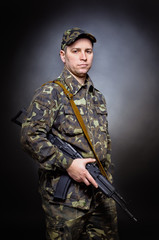 Man in military uniform standing with a gun