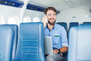 Man enjoying his journey by airplane with laptop and phone