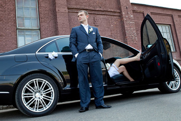 Wedding. Groom next to an executive car which sits bride.