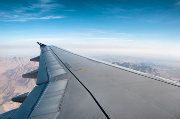 Fototapeta na wymiar Wing of an airplane flying over mountains