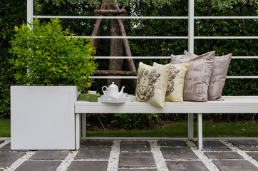 bench in garden with tea set and pillows