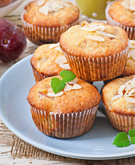 Muffins with plums and almond petals decorated with mint leaves