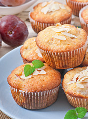 Muffins with plums and almond petals decorated with mint leaves