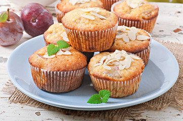 Muffins with plums and almond petals decorated with mint leaves