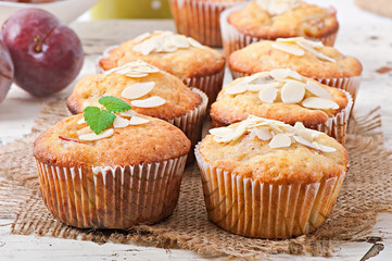 Muffins with plums and almond petals decorated with mint leaves