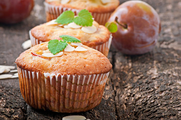 Muffins with plums and almond petals decorated with mint leaves