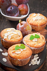 Muffins with plums and almond petals decorated with mint leaves