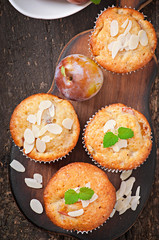 Muffins with plums and almond petals decorated with mint leaves