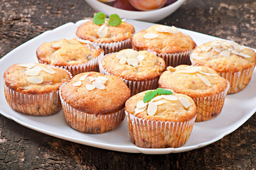 Muffins with plums and almond petals decorated with mint leaves