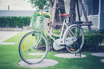 Fototapeta premium retro photo of beautiful artificial flowers in bicycle at garden