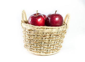 Wicker basket full of apples isolated on white