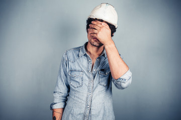 Blue collar worker covering his face - obrazy, fototapety, plakaty