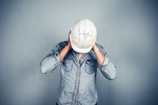 Blue collar worker covering his ears