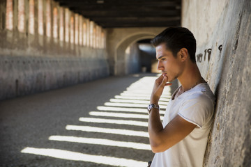 Handsome young man in old building against brick wall