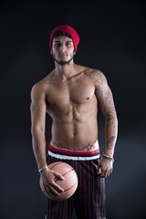 Fototapeta na wymiar Young athletic man on dark background holding basketball ball