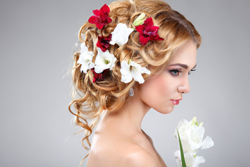 Beautiful girl on a grey with varicoloured flowers  in hairs